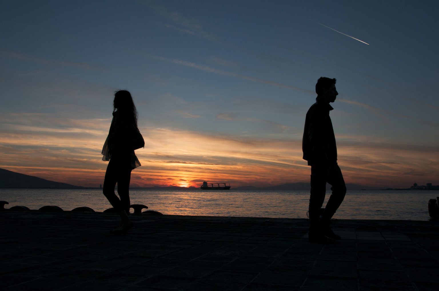 Couple walking away from each other in front of a sunset