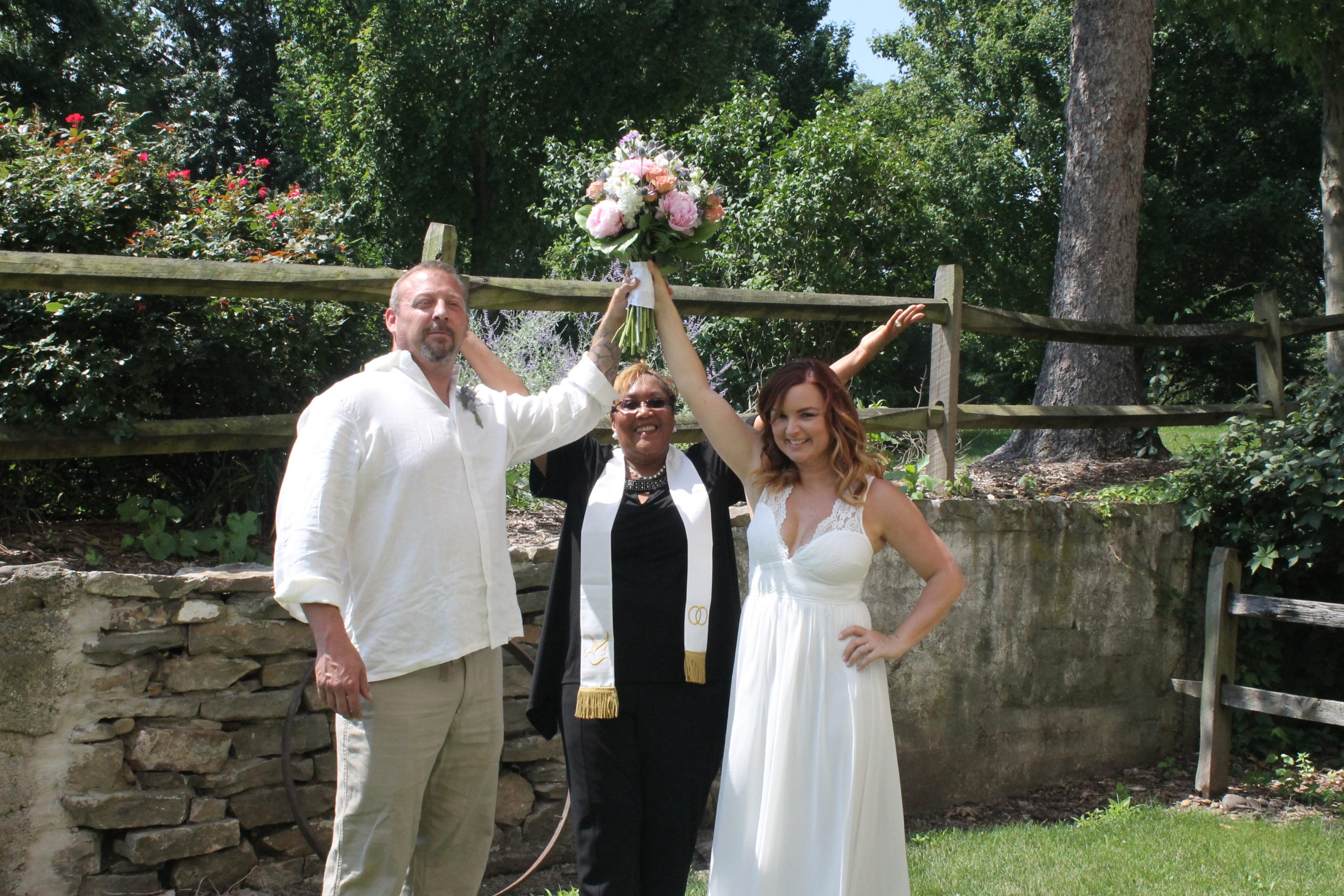 A wedding officiant posing for a picture with a just married couple