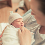 Mother in hospital bed holding newborn baby boy in her arms.